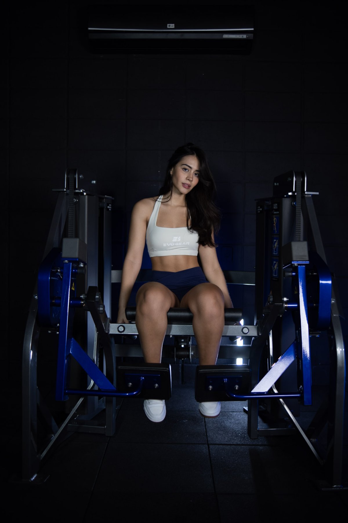 mulher sentada em equipamento de academia de cadeira extensora