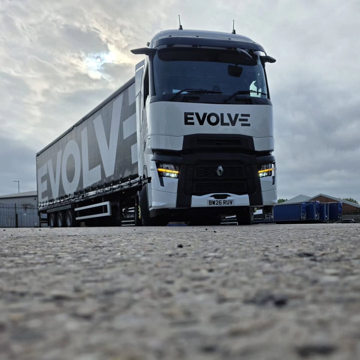 Low-angle view of a white Evolve Renault tractor unit with a black Evolve-branded curtain-sided trailer.