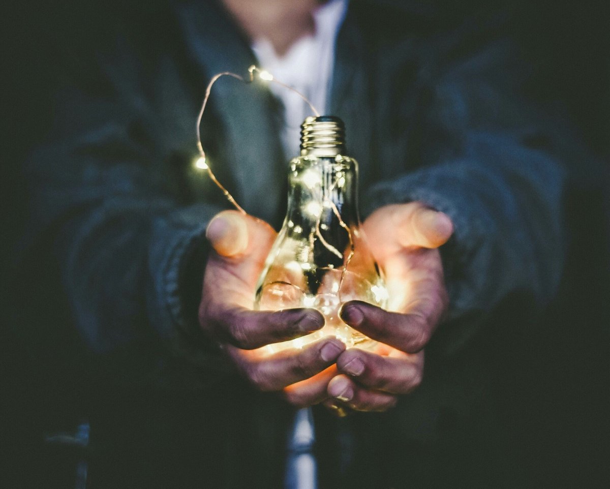Image shows hands cupping a lightbulb image with light escaping signifying trust and a lit pathway